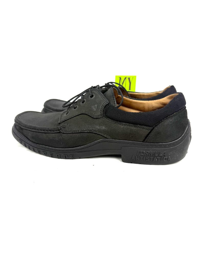 May include: Black leather shoes with laces. The shoes have a rounded toe and a thick sole. The words "Formula Antistatica" are printed on the side of the sole. The shoes are designed for comfort and durability.