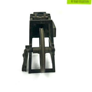 May include: A black metal toy model of a small industrial machine with a wheel and gears. The model is made of metal and has a realistic design.