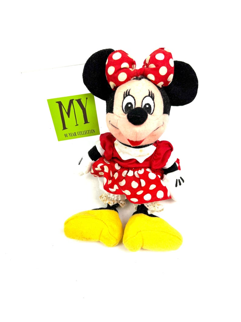 Vintage Minnie Mouse plush doll wearing a red polka dot dress and bow, displayed upright on a white background