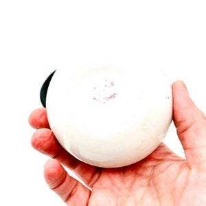 May include: White ceramic round bowl with a pink stamp on the bottom that reads "C.Z.W.T.E."
