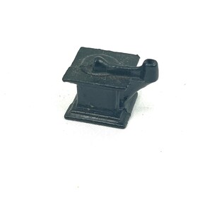 May include: A small, black cast iron stove with a single burner and a pipe for venting smoke. The stove is a miniature replica of a traditional wood-burning stove.