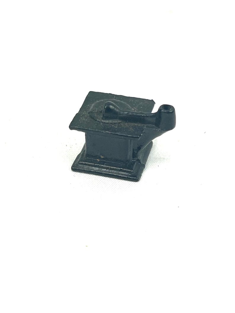 May include: A small, black cast iron stove with a single burner and a pipe for venting smoke. The stove is a miniature replica of a traditional wood-burning stove.