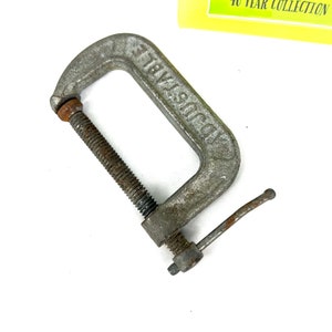 May include: A silver metal C-clamp with a threaded screw and a lever handle. The clamp is labeled "Industrial".