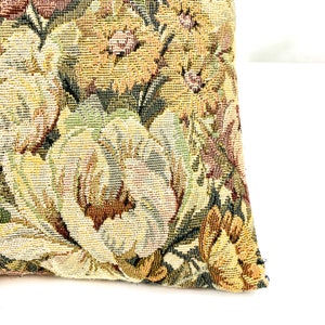May include: A close-up of a tapestry pillow with a floral pattern in shades of brown, green, and yellow.