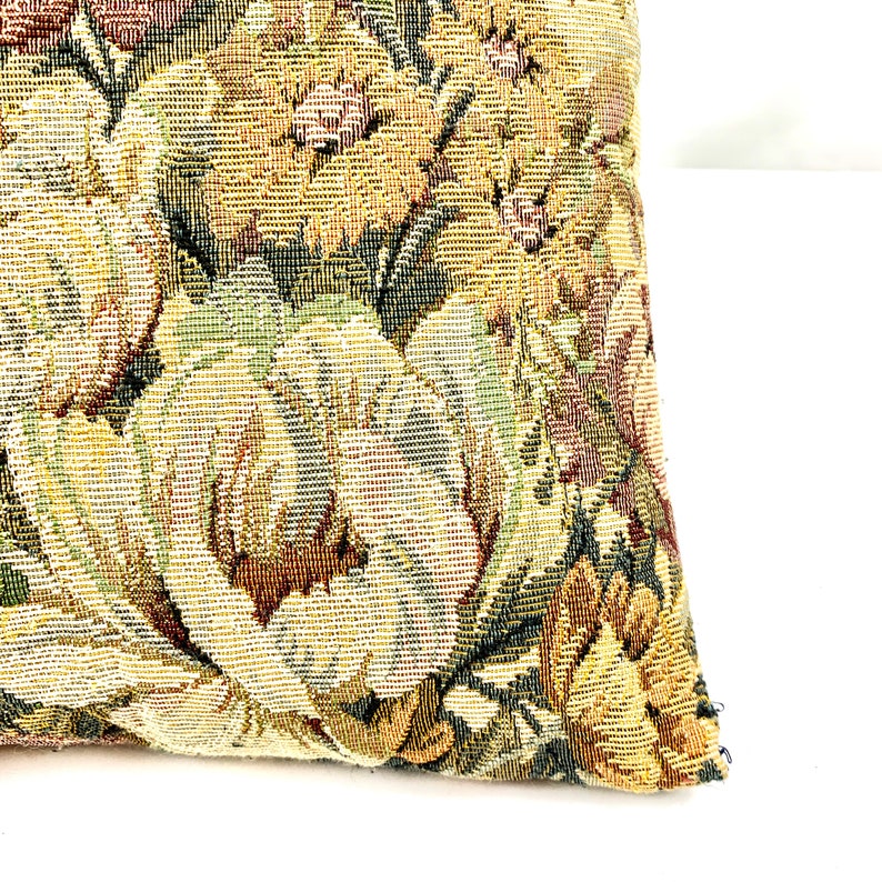 May include: A close-up of a tapestry pillow with a floral pattern in shades of brown, green, and yellow.
