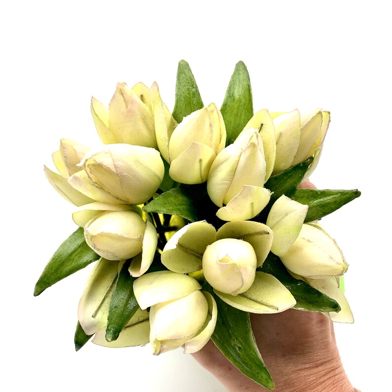 May include: A bouquet of artificial cream-colored tulips with green leaves.
