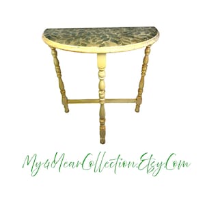 May include: A half-round table with a yellow painted finish and a green leaf design on the top. The table has three legs with turned spindles.