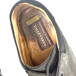 May include: Close-up of a black leather shoe with laces. The shoe's interior features a brown leather insole with the text "VALLEVERDE Personal Comfort made in Italy". The shoe has a black fabric trim.