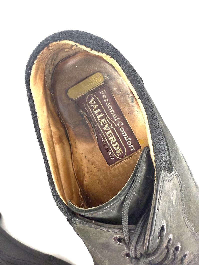 May include: Close-up of a black leather shoe with laces. The shoe's interior features a brown leather insole with the text "VALLEVERDE Personal Comfort made in Italy". The shoe has a black fabric trim.