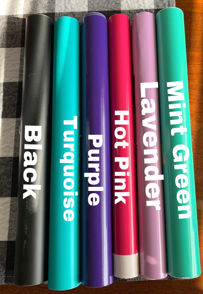May include: A collection of vinyl rolls in various colors, including black, turquoise, purple, hot pink, lavender, and mint green. Each roll is labeled with its respective color name in white text.