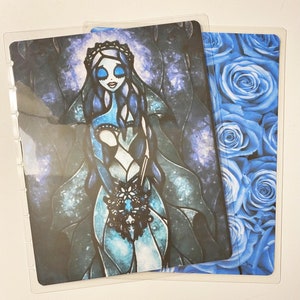 Puede incluir: Una ilustración de estilo vitral azul y negro de una novia con un ramo de flores. El fondo es azul oscuro con estrellas blancas. La imagen está impresa en una lámina de plástico transparente.