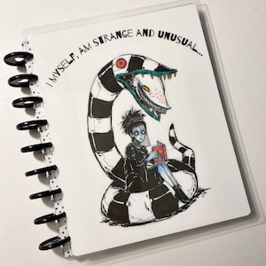 Puede incluir: Una criatura con rayas blancas y negras con una boca grande y dientes afilados se envuelve alrededor de una persona que sostiene un libro rojo. El texto "I myself, am strange and unusual..." está impreso en la página.