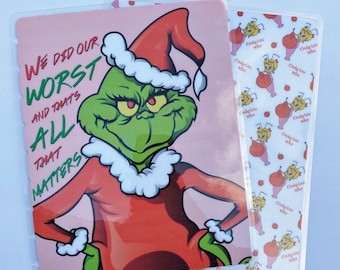 May include: Two clear plastic covers. One features the Grinch in a Santa hat and red outfit with the text "WE DID OUR WORST AND THAT'S ALL THAT MATTERS." The other has a pattern of Cindy Lou Who characters.