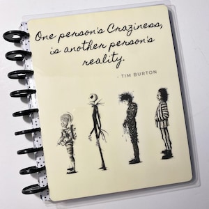 Puede incluir: Una libreta de color crema con una cubierta de plástico transparente. La cubierta presenta una cita de Tim Burton: "La locura de una persona es la realidad de otra." La cita está acompañada de ilustraciones en blanco y negro de personajes de películas de Tim Burton, incluyendo a Jack Skellington, Beetlejuice y Edward Scissorhands.
