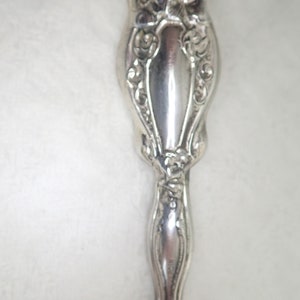 May include: A silver-plated, ornate, decorative handle with a floral design.