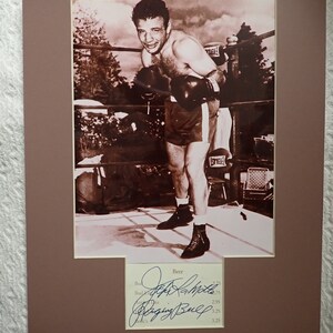May include: A black and white photo of a boxer in a boxing ring. The boxer is wearing boxing gloves and shorts. The photo is signed by "Joe Louis" and "The Brown Bomber".