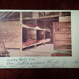 May include: A vintage postcard showing a room with bunk beds and a dresser. The postcard is titled "The Original Pullman" and has a handwritten message that reads "An attractive Hotel Yes - No? Am well and happy, C. Hamming."