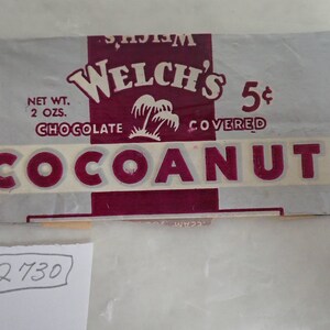 May include: Vintage Welch's Coconut Chocolate candy wrapper. The wrapper is silver with maroon accents and text. The text includes "Welch's", "Chocolate Covered", and "Coconut". The net weight is 2 oz.