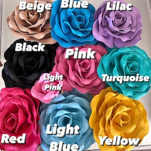 Op de afbeelding: Een verzameling grote, kunstmatige rozenbloemen in verschillende kleuren, waaronder beige, blauw, lila, zwart, roze, turkoois, rood, lichtroze, lichtblauw en geel. Elke bloem heeft meerdere bloemblaadjes en is gelabeld met de kleurnaam.