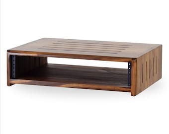 May include: A rectangular, wooden audio equipment rack with a dark brown finish. The top has several parallel slots, and the sides feature vertical grooves. Metal brackets are visible on the sides for mounting equipment. The rack is designed to hold audio components.