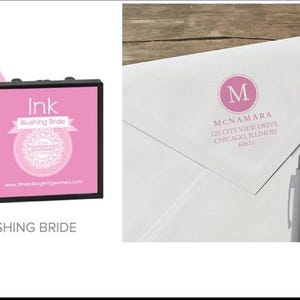 May include: Pink ink pad with the text "Ink Blushing Bride" and a pink drop graphic. A white envelope with a pink monogram and address is next to two pens, one yellow and one gray.