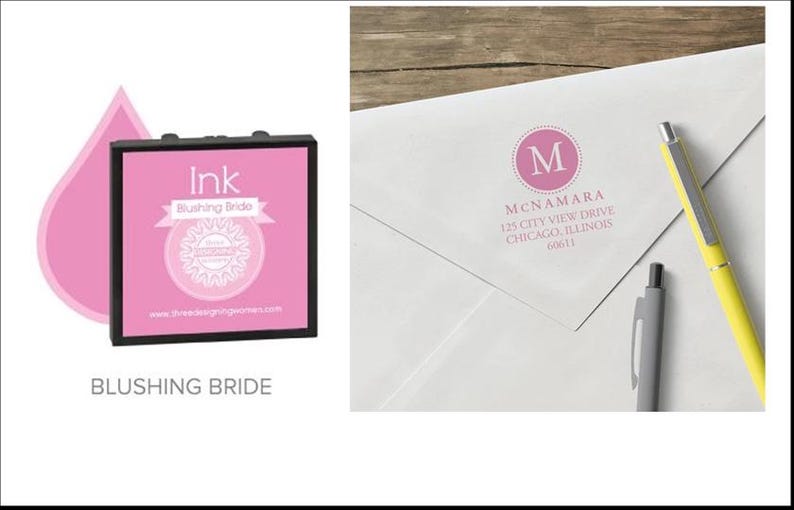 May include: Pink ink pad with the text "Ink Blushing Bride" and a pink drop graphic. A white envelope with a pink monogram and address is next to two pens, one yellow and one gray.
