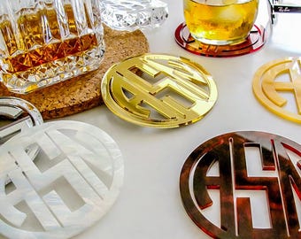 May include: Set of six round coasters with different colors and patterns. Each coaster features a monogram in a circle. The coasters are made of acrylic and have a glossy finish.