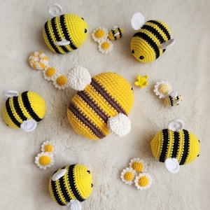 May include: A set of crocheted bee toys with black and yellow stripes. The bees are surrounded by small white crocheted flowers.