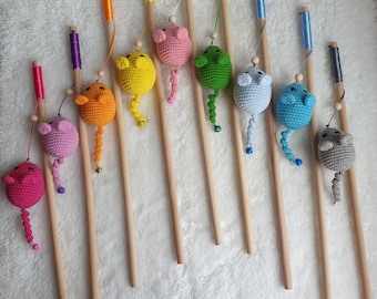 May include: Ten colorful crocheted cat toys on wooden sticks. The toys are shaped like mice and have different colored tails. The sticks are all the same length and are arranged in a row.