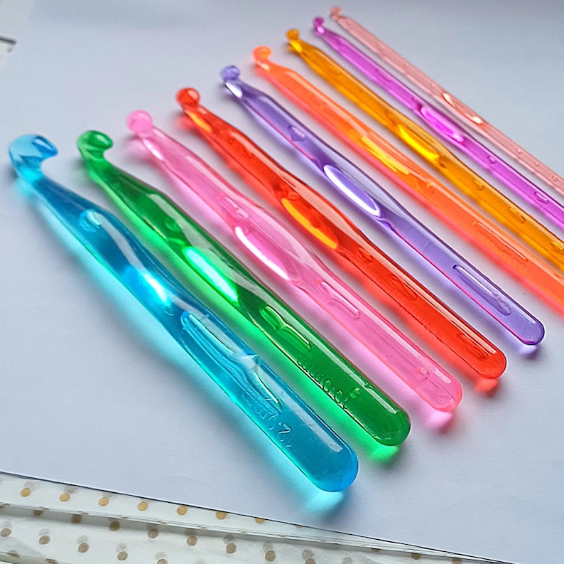 Pu&ograve; includere: Un set di dieci uncinetti in plastica colorati. Gli uncinetti sono disposti in fila dal pi&ugrave; grande al pi&ugrave; piccolo, con l'uncinetto pi&ugrave; grande a sinistra e quello pi&ugrave; piccolo a destra. Gli uncinetti sono tutti di colori diversi, tra cui blu, verde, rosa, arancione, giallo e viola.