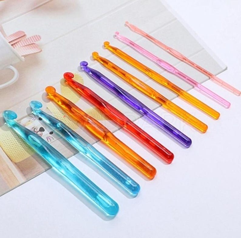 Pu&ograve; includere: Un set di 10 uncinetti di plastica colorati. Gli uncinetti sono disposti in una fila dal pi&ugrave; piccolo al pi&ugrave; grande, con l'uncinetto pi&ugrave; piccolo di colore rosa chiaro e l'uncinetto pi&ugrave; grande di colore blu chiaro.