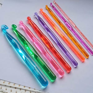 Pu&ograve; includere: Un set di dieci uncinetti in plastica colorati. Gli uncinetti sono disposti in fila dal pi&ugrave; grande al pi&ugrave; piccolo, con l'uncinetto pi&ugrave; grande a sinistra e quello pi&ugrave; piccolo a destra. Gli uncinetti sono tutti di colori diversi, tra cui blu, verde, rosa, rosso, arancione, giallo e viola.