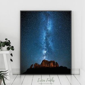 May include: A black framed photograph of a night sky with the Milky Way galaxy visible above a dark silhouette of a mountain range. The image is titled "Erica Fuchs Photography".
