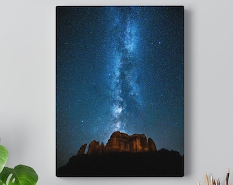 May include: A canvas print depicting a night sky with the Milky Way galaxy visible above a dark mountain range. The stars are bright and the sky is a deep blue.