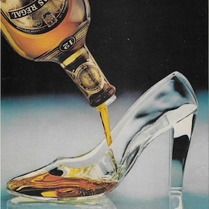 May include: A bottle of Chivas Regal 12 year old blended Scotch whisky being poured into a glass slipper. The bottle has a gold label with the text "Chivas Regal" and "12" printed on it. The text "To send a gift, dial 1-800-528-6148" is printed at the top of the image. The text "Why settle for champagne?" is printed at the bottom of the image.
