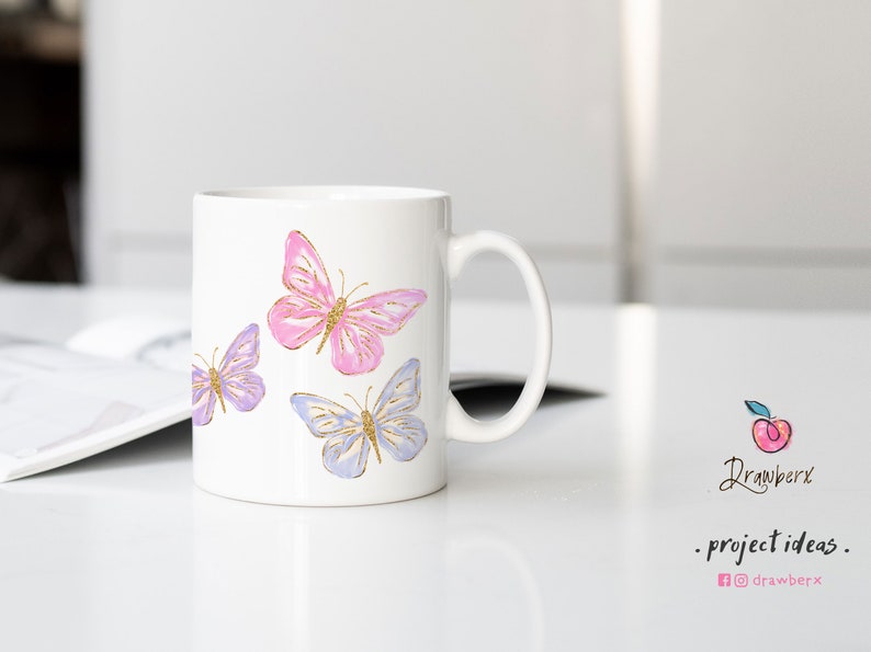Puede incluir: Taza de cer&aacute;mica blanca con tres mariposas pintadas en ella. Las mariposas son de color rosa, morado y azul con detalles de purpurina dorada.