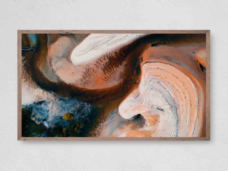 May include: Abstract aerial photograph of a landscape with swirling patterns of white, orange, and brown sand.