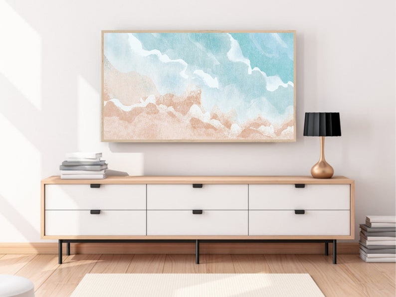 May include: A framed watercolor painting of a beach scene with blue and white waves and a light brown sandy beach.