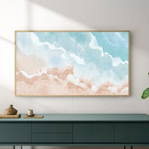 May include: A framed watercolor painting of a beach scene with blue and pink hues. The painting is hanging on a white wall above a dark green dresser.