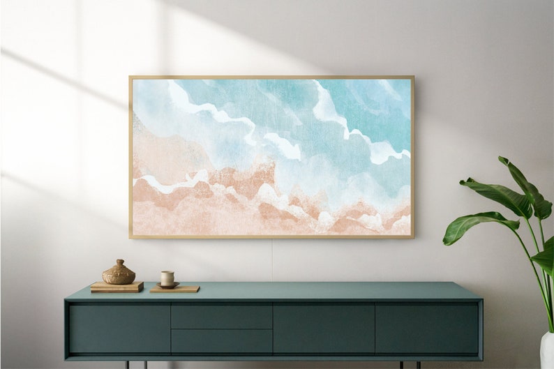 May include: A framed watercolor painting of a beach scene with blue and pink hues. The painting is hanging on a white wall above a dark green dresser.