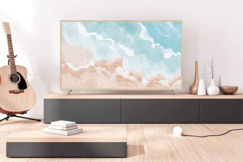 May include: A modern living room interior with a flat screen TV displaying a watercolor painting of a beach scene. The TV is on a dark grey entertainment center with a wooden top. There is a wooden coffee table with a stack of books on it. A white lamp is on the floor.