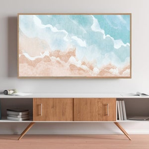 May include: A framed watercolor painting of a beach scene with blue and white waves and a light brown sandy beach.