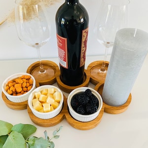 Könnte beinhalten: Ein Holztablett mit sechs Fächern, zwei für Weingläser, eines für eine Weinflasche und drei für Snacks. Das Tablett enthält eine graue Kerze, eine Schale mit Käsewürfeln, eine Schale mit orangen Snacks und eine Schale mit Brombeeren.