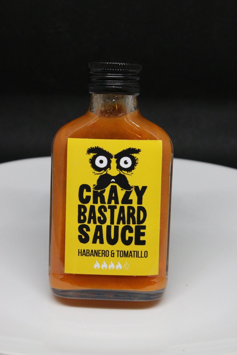 May include: A yellow bottle of hot sauce with a black label that says "Crazy Bastard Sauce" with a cartoon face and the words "Habanero & Tomatillo" and four flames.