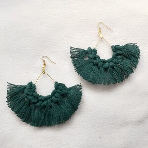 May include: A pair of green tassel earrings with gold hoops. The earrings are handmade and feature a fringe design.
