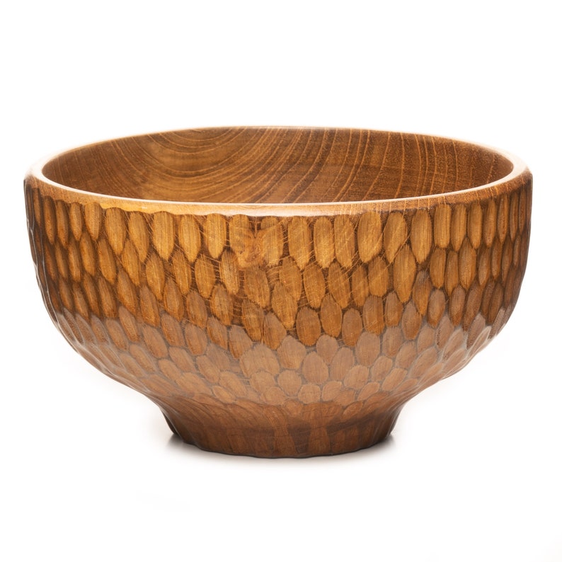 May include: A large, wooden bowl with a unique, textured design. The bowl is made of dark brown wood and has a honeycomb pattern carved into the surface.