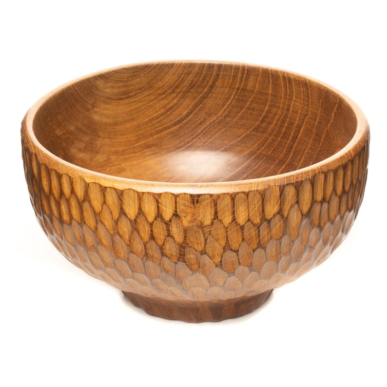 May include: A large, wooden bowl with a textured, honeycomb-like pattern on the exterior. The bowl is made of light brown wood and has a smooth, rounded interior.