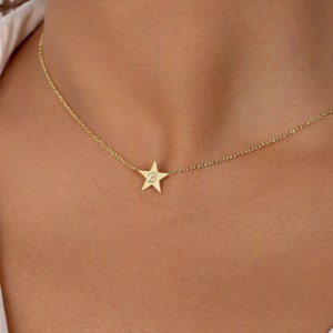 May include: A gold chain necklace with a small gold star pendant. The star has a small diamond in the center.