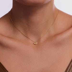 May include: A gold chain necklace with a small bee pendant adorned with tiny clear stones.