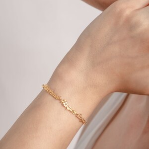 May include: Gold bracelet with the names "Michael", "Harper", and "Logan" engraved on it.